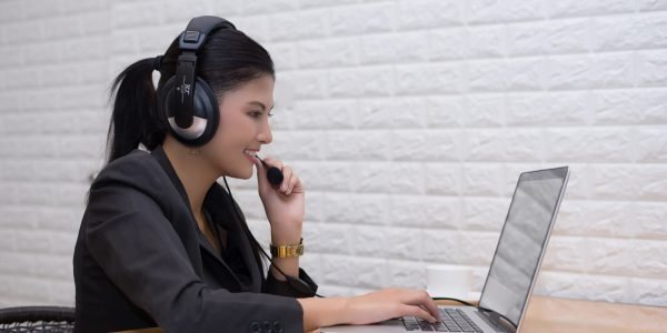 Young businesswoman with headset sitting at office table